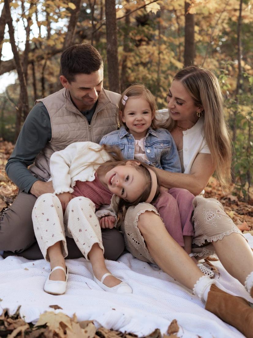 A family of four tumbling together on a blanket in the fall leaves