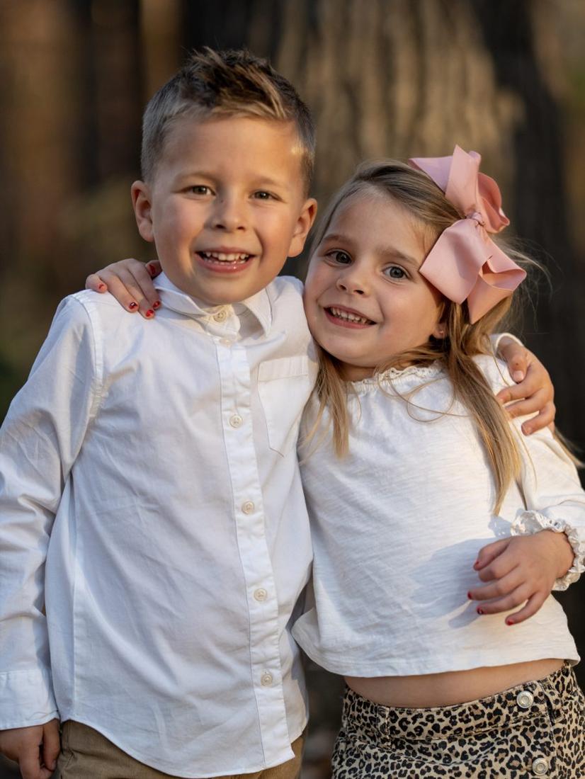 A brother and sister grinning, arms around each other