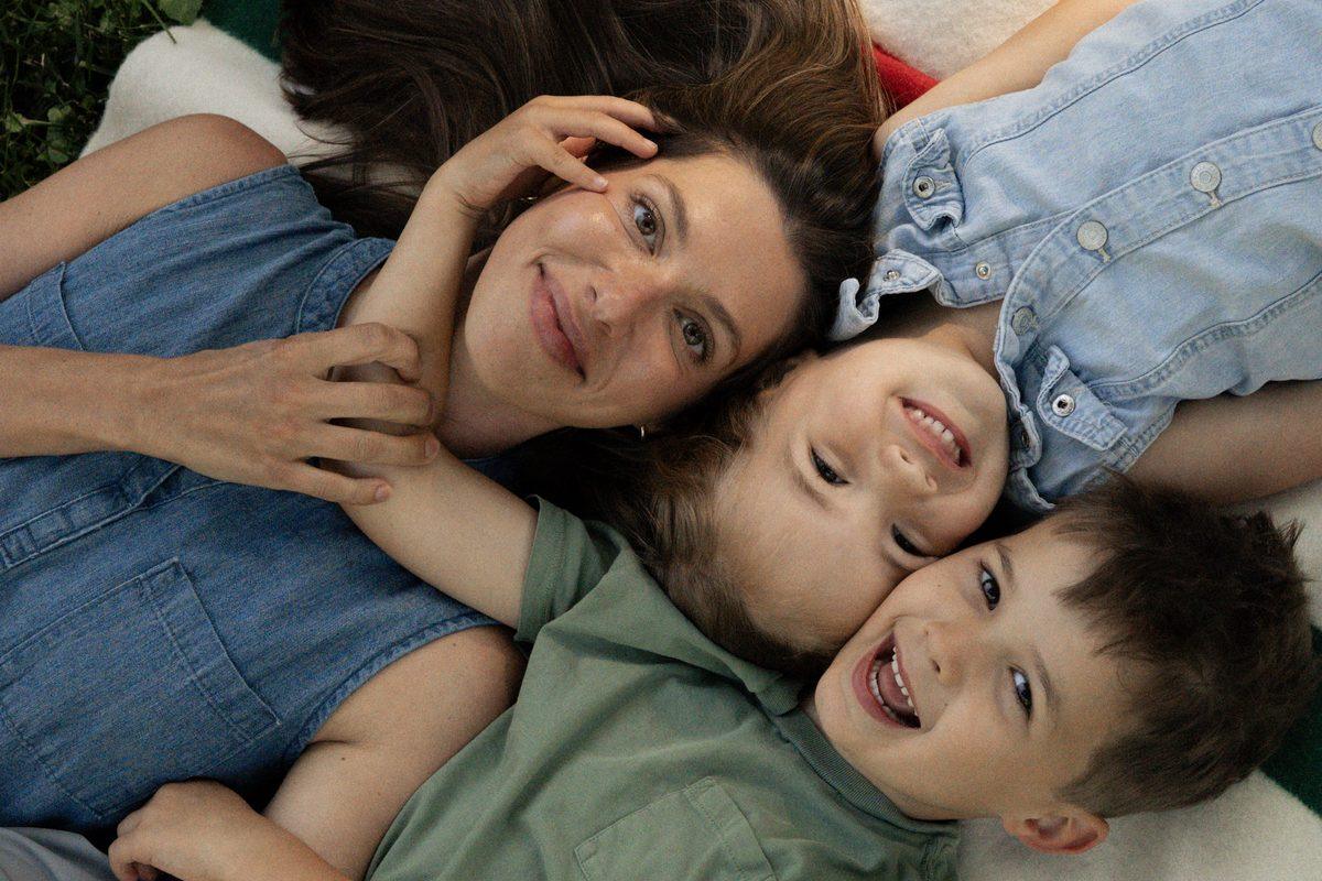 A mom lying with her two kids, all laughing